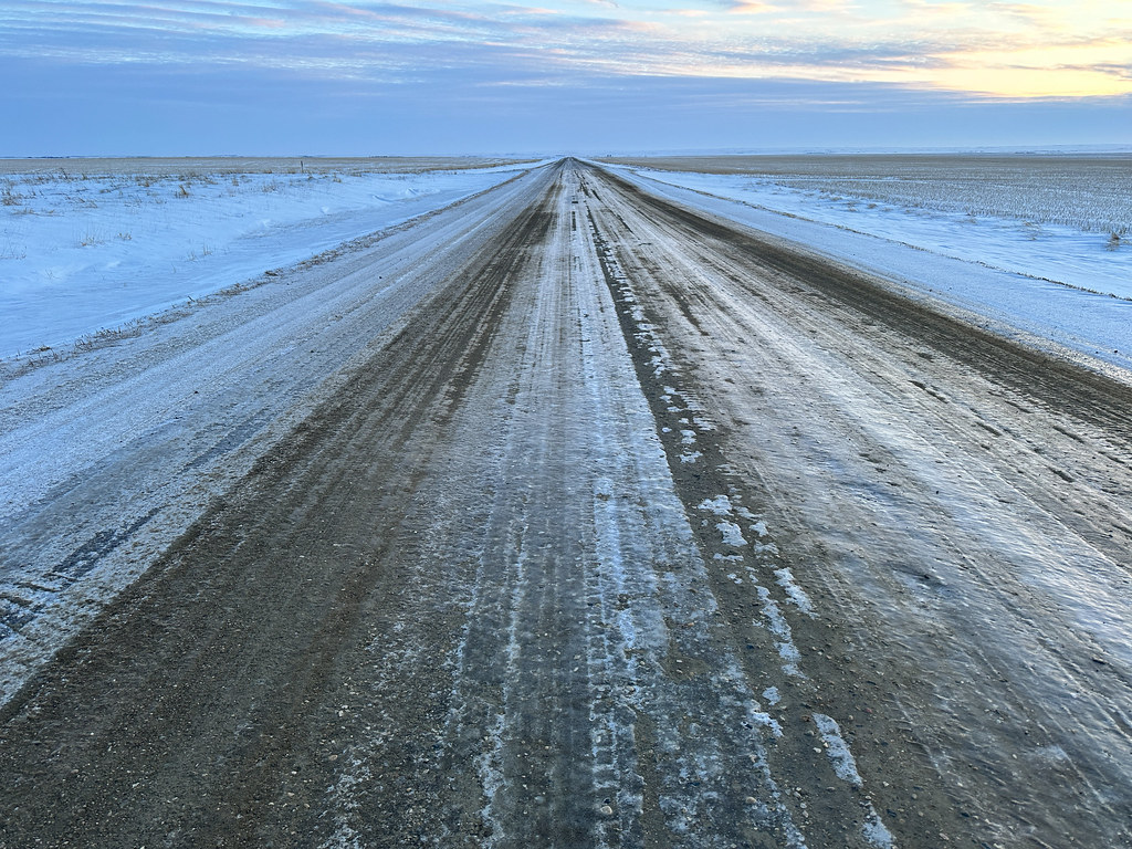 An empty frozen road stretching toward the horizon